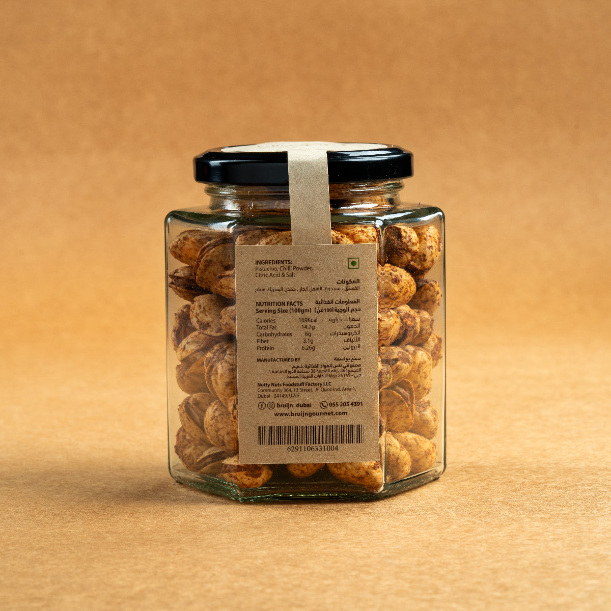 Glass jar of Bruijn Persian Lime & Chilli Pistachios with black lid and kraft label, filled with spiced pistachios coated in lime and chilli seasoning.