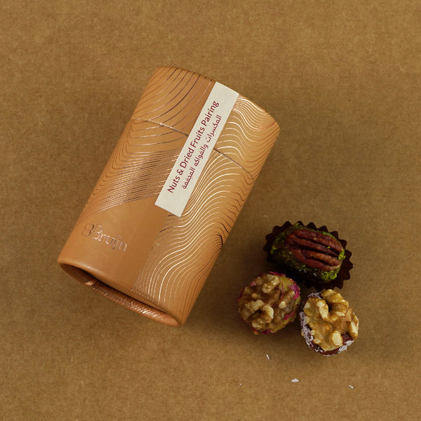 Golden cylindrical container of Bruijn stuffed walnut and pecan dried fruit wholes, placed beside whole pecans and walnuts stuffed with dates and pistachios.