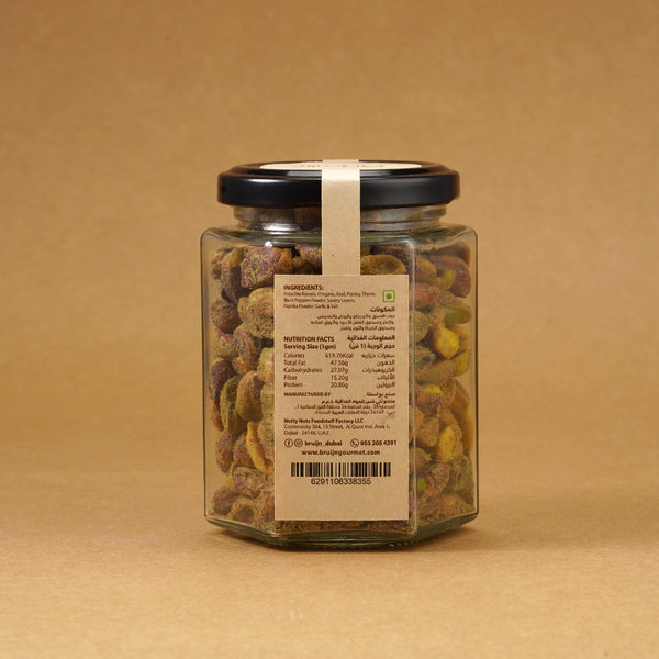 Glass jar of Bruijn Chimichurri Pistachios with black lid and kraft label, filled with pistachios coated in green herb and spice chimichurri seasoning.