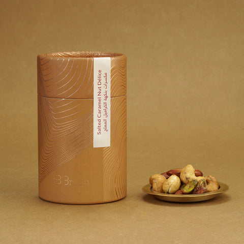Brown cylindrical container of Bruijn Salted Caramel Nut Délice with minimalist design, containing a golden caramel-coated mix of cashews, almonds, and pistachios.